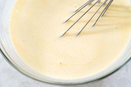 Mixing ingredients in a glass mixing bowl to prepare coconut banana pancakes.