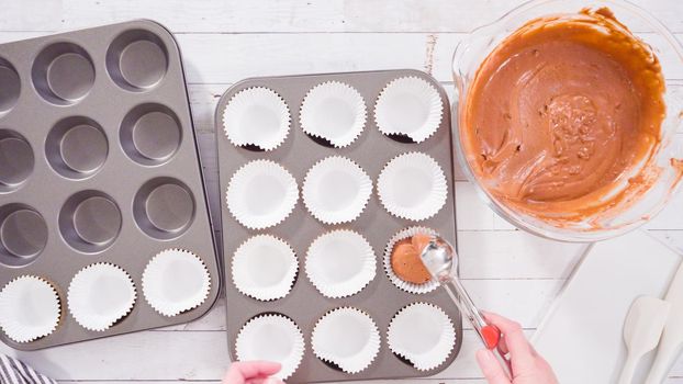 Flat lay. Scooping dough into the foil cupcake liners to bake chocolate raspberry cupcakes.