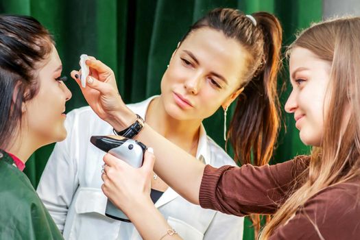 Makeup artist making professional makeup on the face of a young woman using an airbrush