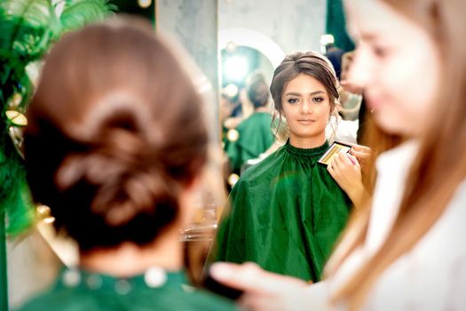 Make-up artist doing makeup for young beautiful bride applying wedding makeup in a beauty salon