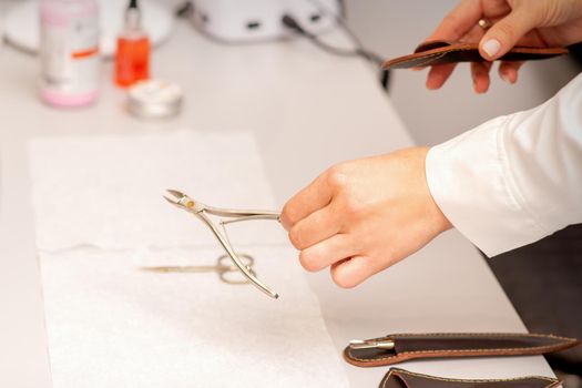 Nail nippers in the hand of female manicure master putting to the towel before nail care in manicure salon