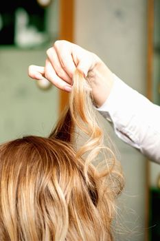 Female coiffeur fixing hairstyling of blonde woman with hairspray in a beauty salon