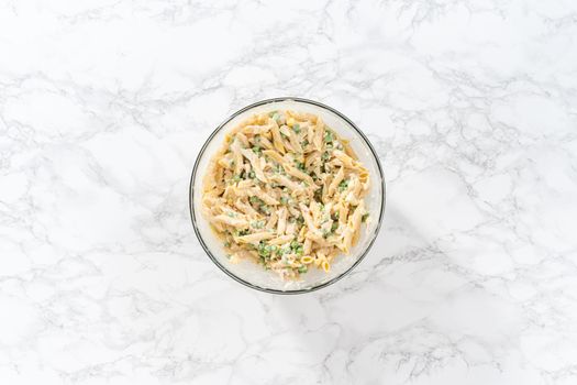 Flat lay. Mixing ingredients in a large glass mixing bowl to make macaroni salad with chicken.