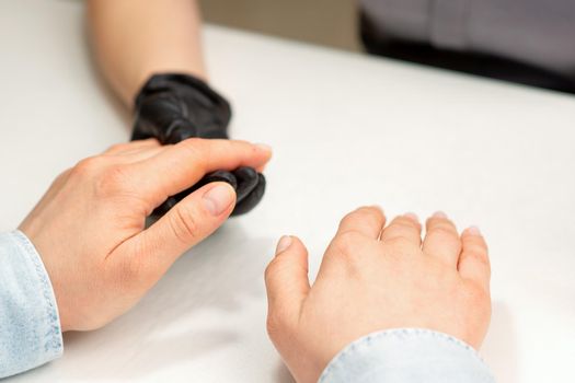 Closeup of manicure master prepares hands of a young woman for manicure procedures