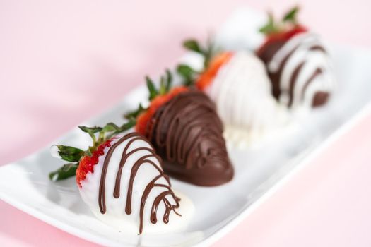 White and dark chocolate dipped strawberries on a white serving plate.