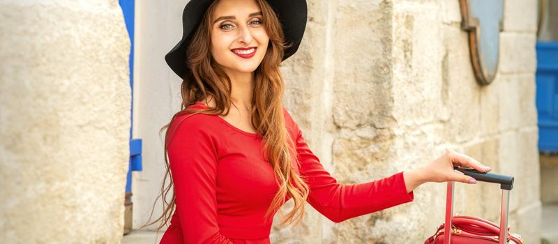 Beautiful young caucasian woman in black hat smiling and sitting on stairs at the door outdoors