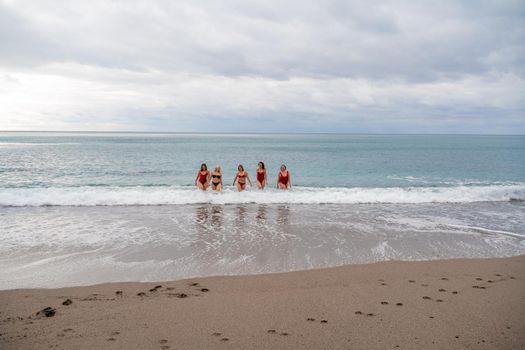 Big happy family or group of five friends is having fun against sunset beach. Beach holidays concept