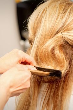 A hairdresser is combing female hairstyling in a hairdressing beauty salon