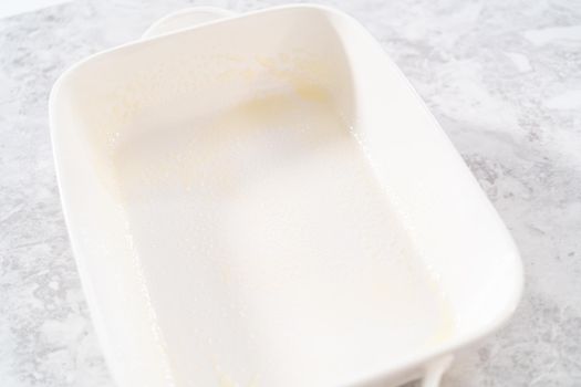 Greasing white casserole dish to bake bread pudding.