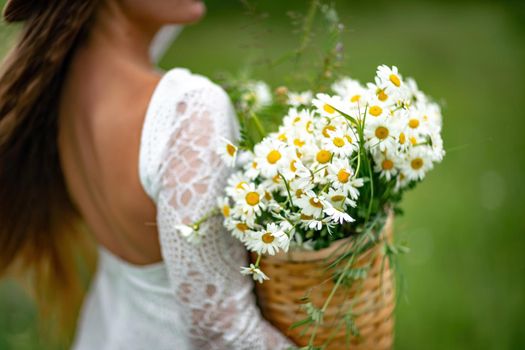 A middle-aged woman holds a large bouquet of daisies in her hands. Wildflowers for congratulations.