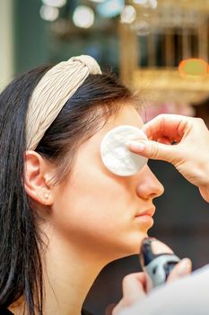 Makeup artist making professional makeup on the face of a young woman using an airbrush