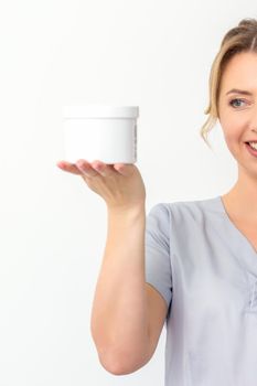 Beautician holding a jar of wax for depitation smiling on a white background. Natural product for hair removal. Copy space