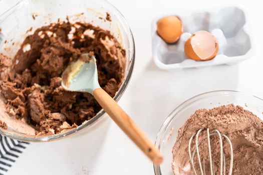 Mixing ingredients in a glass mixing bowl to bake chocolate cookies.
