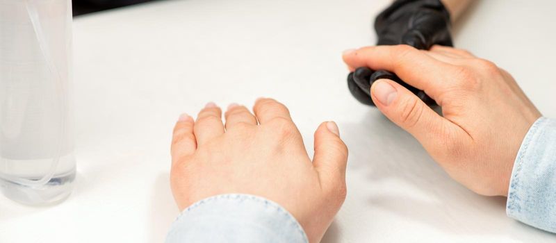 Closeup of manicure master prepares hands of a young woman for manicure procedures