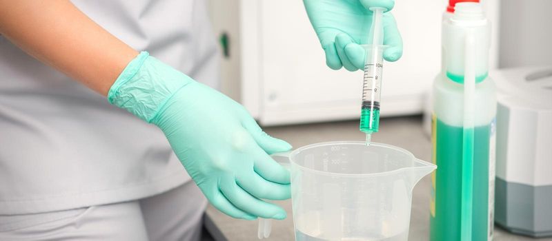 The beautician uses a syringe to add disinfectant to the water. Sterilization of tools