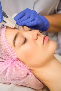 Young caucasian woman having ultrasonic peeling with ultrasound device in a cosmetic beauty salon