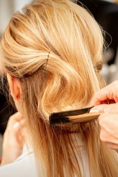 A hairdresser is combing female hairstyling in a hairdressing beauty salon