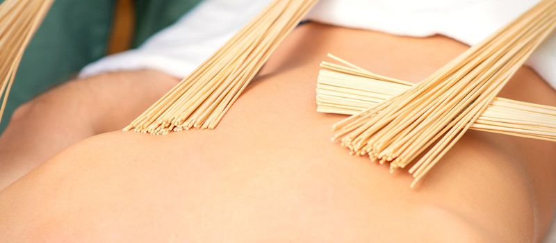 Young man have double samurai massage with bamboo brooms in spa. Relaxation massage concept
