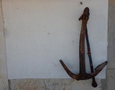 Old ship anchor leaning against a white wall