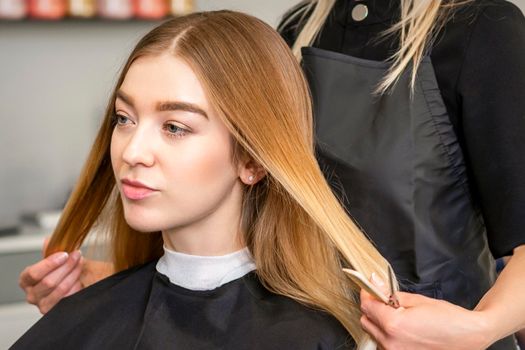 Hair stylist's hands doing professional hairstyling of female long hair in a beauty salon