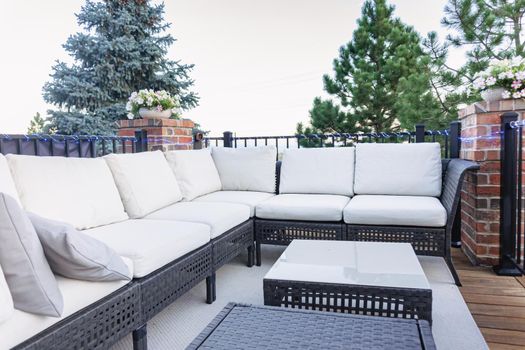 Morning on a summer day. Fully furnished backyard patio with a grill, sitting area, and umbrella.