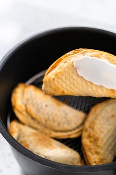 Frying sweet cherry empanadas in the air fryer.