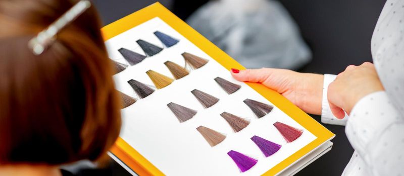 Young caucasian woman choosing a color from the hair color chart in a beauty salon