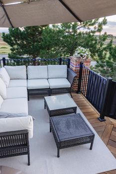 Morning on a summer day. Fully furnished backyard patio with a grill, sitting area, and umbrella.