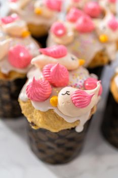 Freshly baked mini Easter bread kulich with lemon glaze, decorated with sprinkles and meringue bird-shaped cookies.