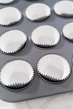 Lining baking cupcake pan with foil liners to bake lemon cupcakes.