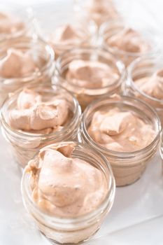 Scooping mixture into the small glass jars to make homemade chocolate ice cream.