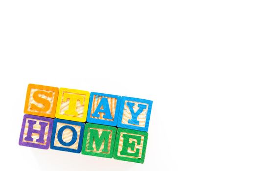 STAY HOME sign out of kids' alphabet blocks on a white background.