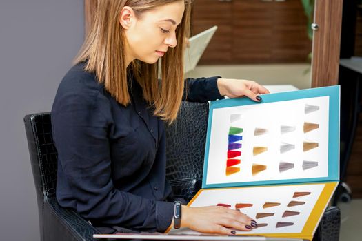 Young caucasian woman choosing a color from the hair color chart in a beauty salon