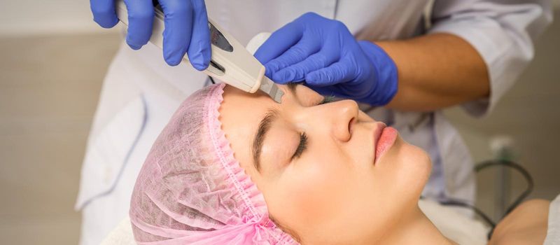 Young caucasian woman having ultrasonic peeling with ultrasound device in a cosmetic beauty salon