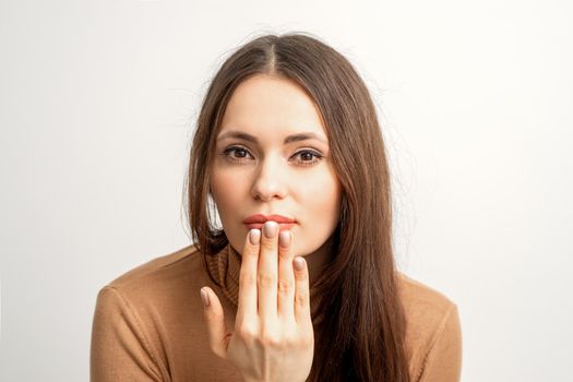 Young caucasian woman posing with fashion beige nails and sensual lips in studio