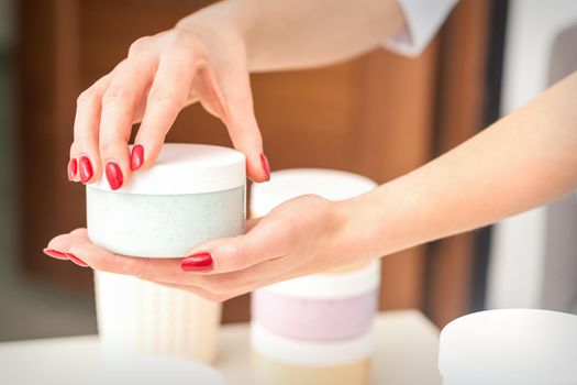 The woman opens the lid holding a jar of moisturizing cream, mockup, copy space, closeup