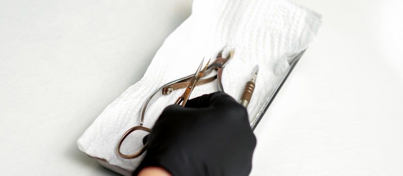 Professional manicure master prepares nail care tools on a white background with copy space