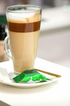 A cup of latte with candy on a saucer on the table in the manicure room. Manicure master place