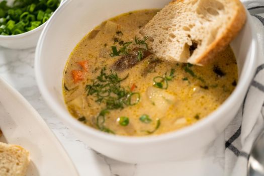 Serving creamy wild mushroom soup made out of dehydrated wild mushrooms in white bowls with sourdough bread.