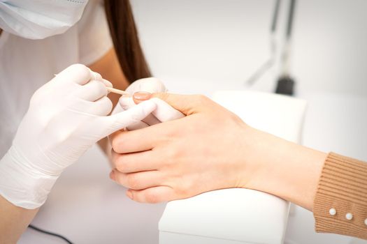 Young woman receiving pink or beige nail polish in a beauty salon