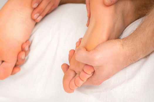 Relaxing double massage on the female feet by two masseurs in spa salon