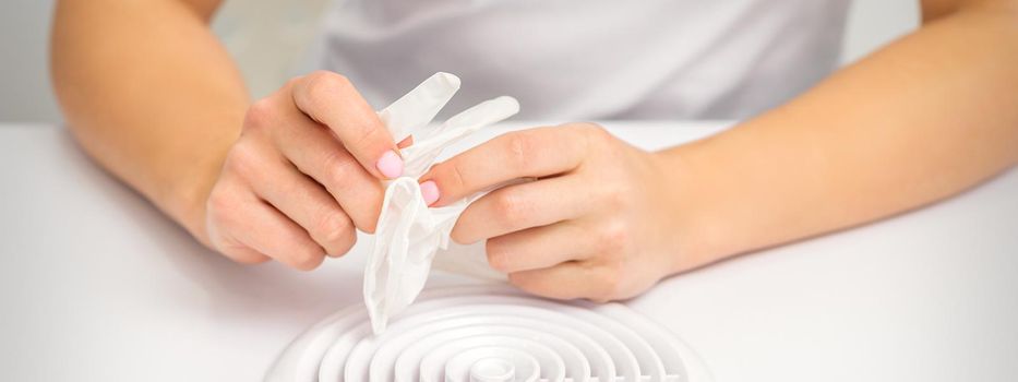 Beautician, doctor, or manicurist holds white latex protective gloves while preparing to wear them before providing services