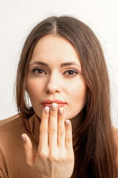 Young caucasian woman posing with fashion beige nails and sensual lips in studio