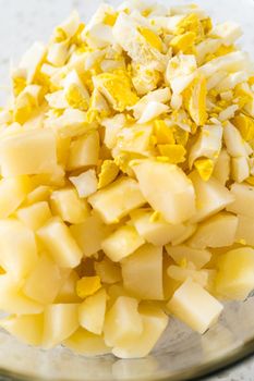 Mixing ingredients in a large glass mixing bowl to make potato salad.