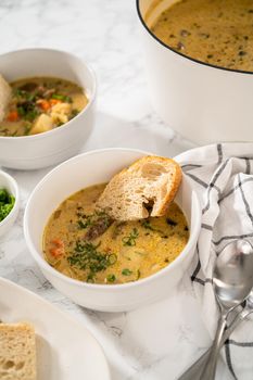 Serving creamy wild mushroom soup made out of dehydrated wild mushrooms in white bowls with sourdough bread.