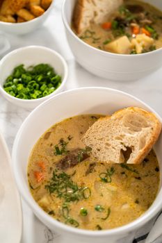 Serving creamy wild mushroom soup made out of dehydrated wild mushrooms in white bowls with sourdough bread.