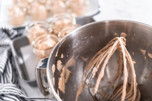 Scooping mixture into the small glass jars to make homemade chocolate ice cream.