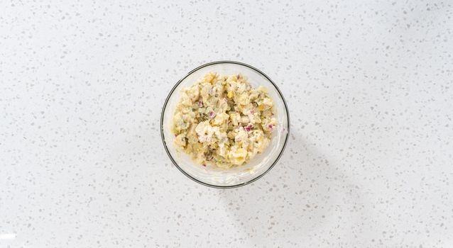 Flat lay. Mixing ingredients in a large glass mixing bowl to make potato salad.