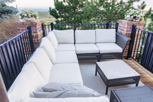 Morning on a summer day. Fully furnished backyard patio with a grill, sitting area, and umbrella.