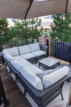 Morning on a summer day. Fully furnished backyard patio with a grill, sitting area, and umbrella.